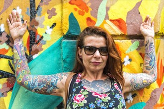 Tattooed woman in front of a wall covered with graffiti