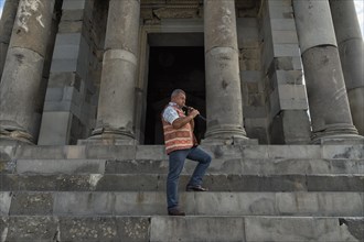 Armenian playing the traditional duduk in front of the Hellenistic Temple of the Sun in Garni