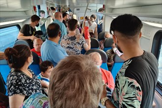 Very many people standing overcrowded in a local train