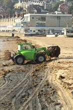 Merlo loader clearing seaweed from the sandy beach of the coastal town of Swanage