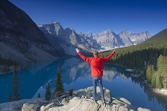 Tourist with open arms at the viewpoint overlooking Moraine Lake in the Valley of the Ten Peaks