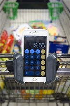 Smartphone with calculator app in a holder of a shopping trolley