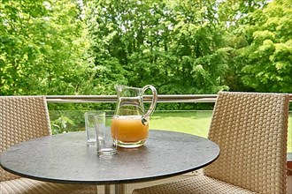 Glass jug with orange juice and two glasses on the terrace of a holiday flat