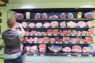 Employee sorting goods at the sausage and meat product shelf