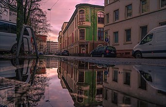 View of the historic Kolmar and Jourdan building after rain with reflection in puddle