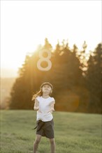 Girl in the meadow throws an 8 ball in the air