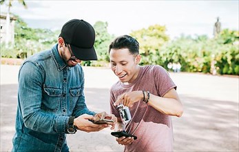 Two happy friends looking at a cell phone in the street