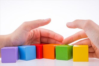 Hand playing with colorful cubes on a white background