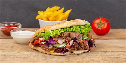 Doener Kebab Doner Kebap fast food meal in pita bread with fries on wooden board Panorama in Stuttgart