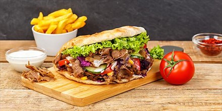 Doener Kebab Doner Kebap fast food meal in pita bread menu with fries on wooden board Panorama in Stuttgart