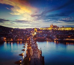 Vintage retro hipster style travel image of night aerial view of Prague castle and Charles Bridge over Vltava river in Prague