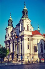 Vintage retro hipster style travel image of St. Nicholas church at Old Town Square early in morning