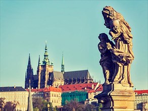 Vintage retro hipster style travel image of statue on Charles Brigde with St. Vitus Cathedral in background in Prague