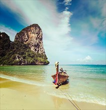 Vintage retro effect filtered hipster style travel image of long tail boat on tropical beach