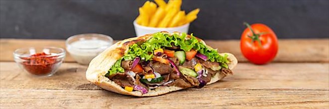 Doener Kebab Doner Kebap fast food meal in pita bread menu with fries on wooden board Panorama in Stuttgart