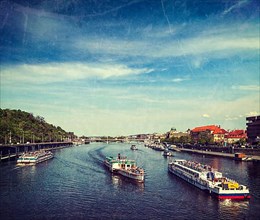 Vintage retro hipster style travel image of turist boats on Vltava river in Prague