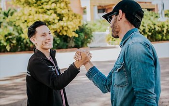 Two people shaking hands on the street. Two teenage friends shaking hands at each other outdoors. Concept of two friends greeting each other with handshake on the street