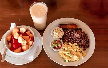 Gallo pinto breakfast served on the table with a fruit salad
