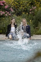 Couple sitting at the edge of the pool and splashing water