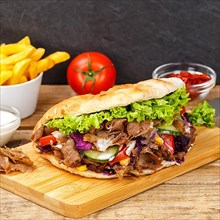 Doener Kebab Doner Kebap fast food meal in pita bread menu with fries on wooden board square in Stuttgart