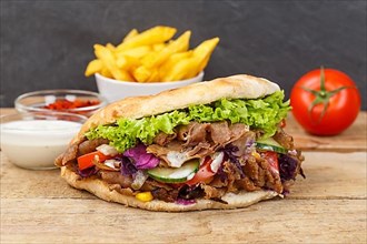 Doener Kebab Doner Kebap fast food meal in pita bread with fries on wooden board in Stuttgart