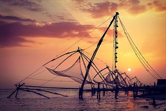 Vintage retro hipster style travel image of Kochi chinese fishnets on sunset. Fort Kochin