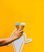 Hand holding two waffle cone ice cream isolated. Hand holding two ice cream cone on yellow background. Waffle cone ice cream concept on yellow background
