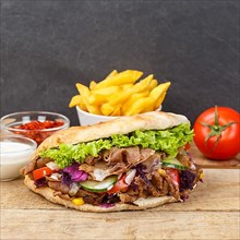 Doener Kebab Doner Kebap fast food meal in pita bread menu with fries on wooden board square with text free space Copyspace in Stuttgart