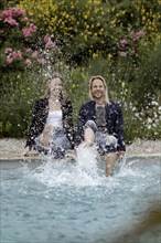 Couple sitting at the edge of the pool and splashing water