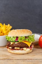 Hamburger cheeseburger fast food meal menu with fries on wooden board with text free space Copyspace in Stuttgart