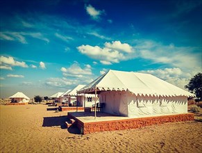 Vintage retro hipster style travel image of luxury tents in desert. Jaisalmer