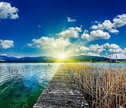 Pier in the lake in countryside on sunset with sunrays