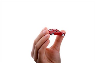 Child's hand holding a red car on a white background