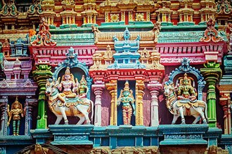 Vintage retro hipster style travel image of Shiva and Parvati on bull images. Sculptures on Hindu temple gopura tower. Meenakshi Temple
