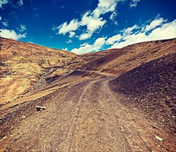 Vintage retro effect filtered hipster style travel image of dirt road in mountains Himalayas. Spiti Valley