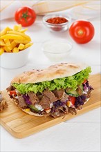 Doener Kebab Doner Kebap fast food meal in pita bread menu with fries on kitchen board in Stuttgart
