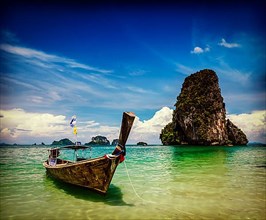 Vintage retro effect filtered hipster style travel image of long tail boat on tropical beach Pranang and rock