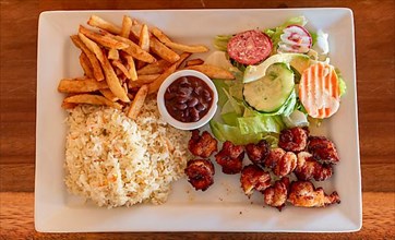 Plate of breaded shrimp with rice and salad on the wooden table. Top view of breaded shrimp with french fries and salad served on wooden table. Seafood food concept served on the table