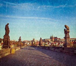 Vintage retro hipster style travel image of Charles bridge and Prague castle in the early morning with grunge texture overlaid. Prague