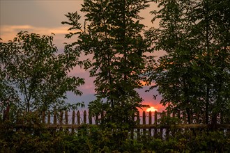 Rural wooden fence against the backdrop of the setting sun