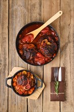 Overhead composition with ossobuco in pan on wooden table