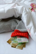 Banknotes in stocking under duvet