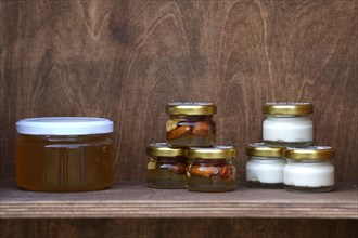 Nuts and honey in small jars on shelf