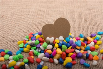 Paper heart amid colorful pebbles on canvas ground