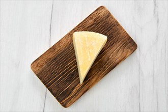 Top view of triangular piece of goat cheese on wooden cutting board