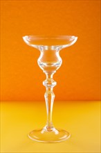 Empty glass for cocktail or dessert on orange background