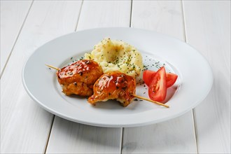 Roasted chicken fillet on skewer with barbecue sauce and mashed potato on white wooden table