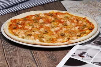 Pizza with salmon and olives on wooden table
