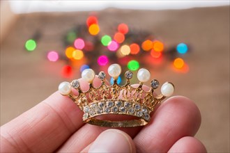 Little crown in hand with colorful lights behind