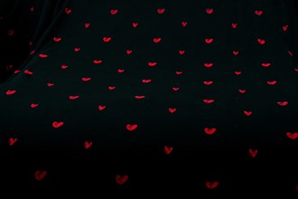 Black fabric background with red hearts shapes